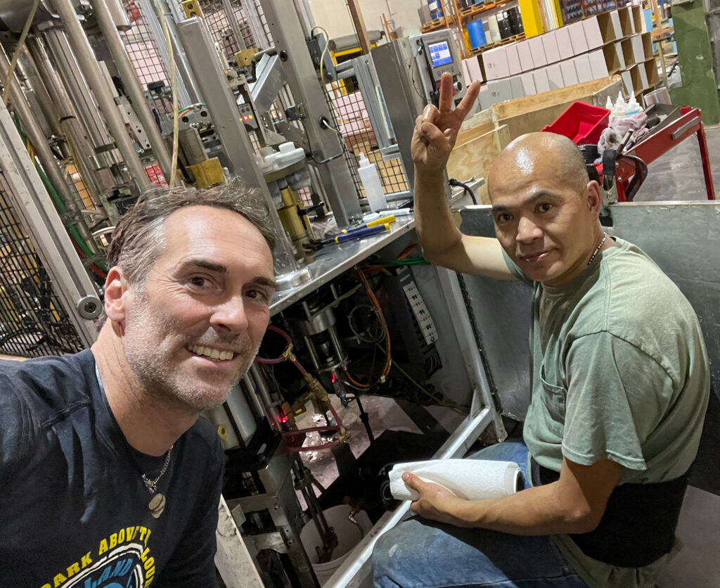 Jason Lynch photographing Chin Lin as he works on a squeeze tube filling machine